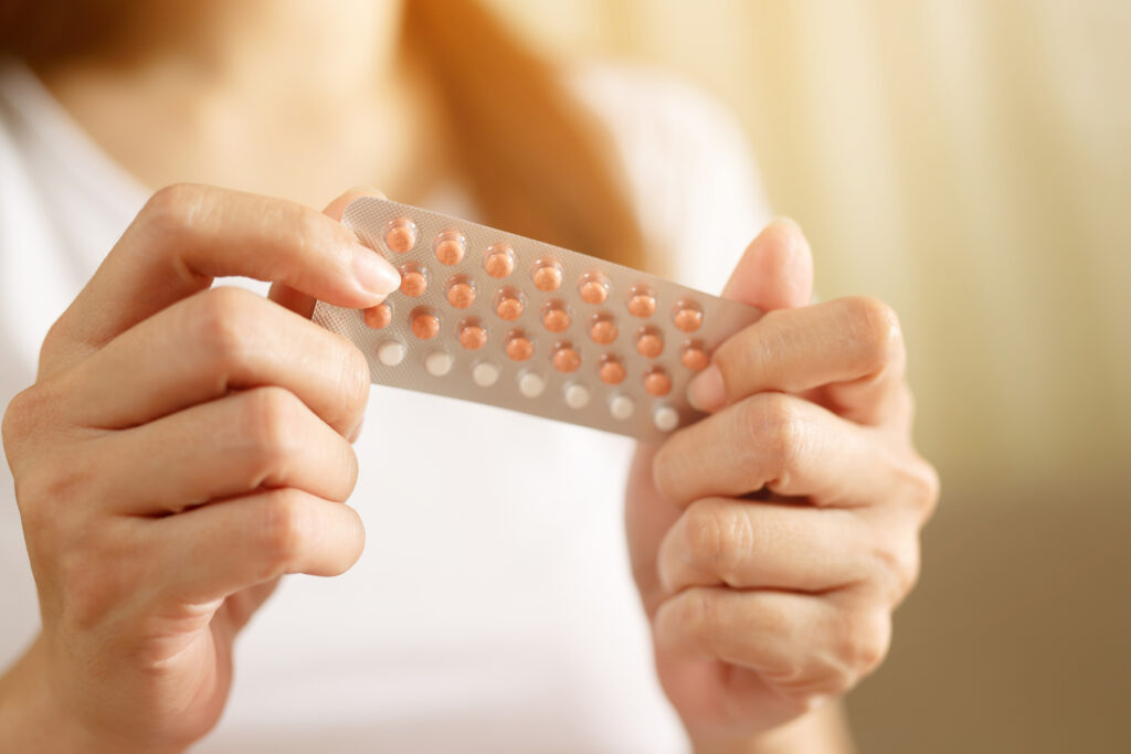 Woman hands opening birth control pills in hand