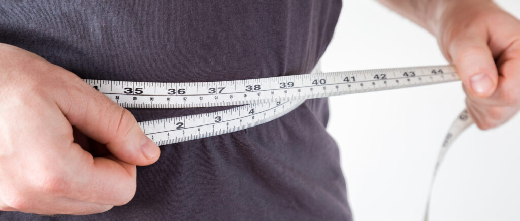 Person measuring their waist with measuring tape